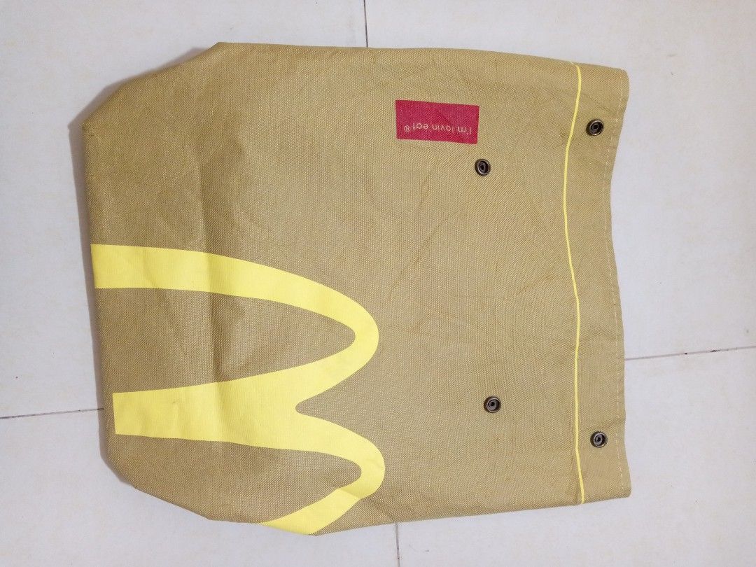 McDonald's Brown Canvas Tote Backpack (Category: Backpacks) located in Manila. Submitted by adrianloqu02215 (Listing ID 1465903065, Image 2). Description: - Brand: McDonald's - Material: Durable heavy-duty canvas fabric in a neutral brown earth-tone - Design: Large yellow golden arches logo on the front with a red 'i'm lovin' it' tag - Closure: Secure snap button closure on the upper section - Straps: Comfortable, adjustable back straps.