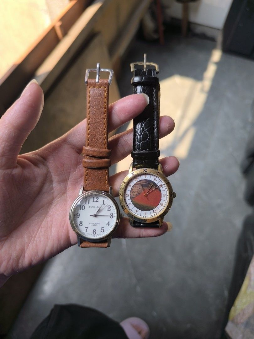 Preloved Men's Watch (Category: Men's Watches) located in Manila. Submitted by sxynss (Listing ID 1465858840, Image 2). Description: - Set of 2 working quartz wristwatches - Watch 1: Sun Flame model, white Arabic numeral dial, brown leather strap - Watch 2: Gold-tone distressed case, Japanese art Mount Fuji dial with zodiac symbols, black faux leather strap - Both watches have working hands - Straps show normal signs of wear.