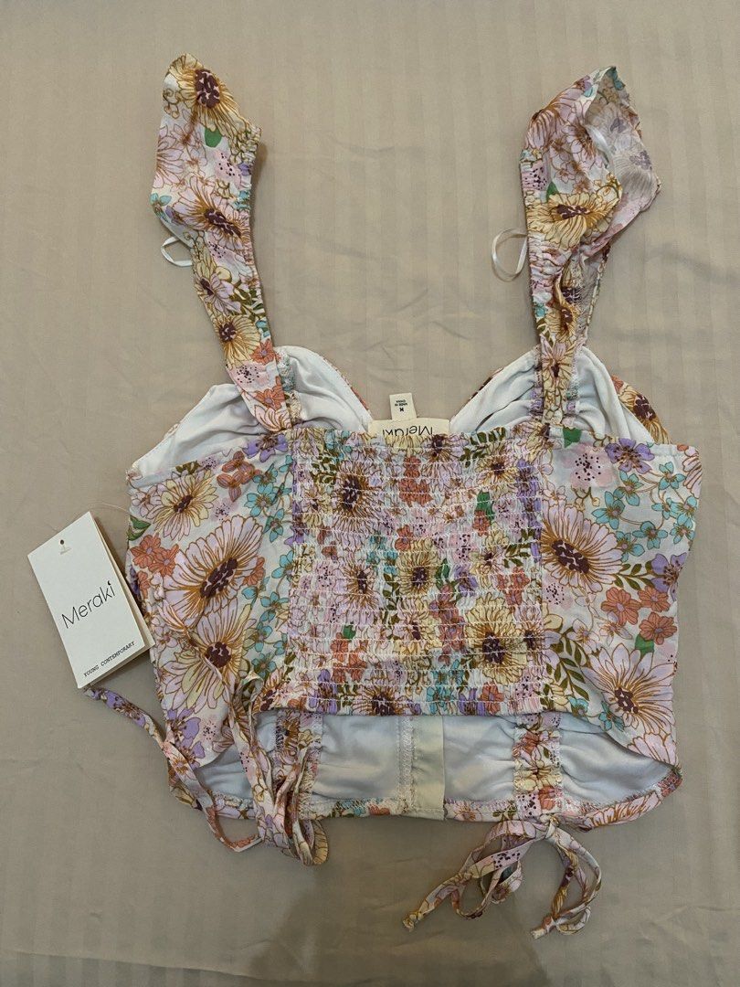 Meraki Floral Crop Top Size M (Category: Sleeveless) located in Cebu City. Submitted by hailey_sells (Listing ID 1465820034, Image 2). Description: - Item: Floral Print Crop Top - Size: Medium - Condition: Brand new with tags (BNWT) - Details: Front hook-and-eye closure, ruched bodice, and adjustable tie hems - Straps: Cute ruffled shoulder straps.