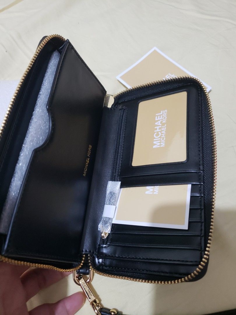 Michael Kors Black Zip Around Wallet With Wristlet Strap (Category: Wallets & Card holders) located in Navotas City. Submitted by miloklo (Listing ID 1465842667, Image 3). Description: Black Michael Kors zip around wallet. Gold tone hardware and matching wristlet strap. Interior holds multiple card slots, slip pockets, and a zippered coin compartment. Protective foam inserts and brand cards still inside. Clean black lining throughout. Zip closure
