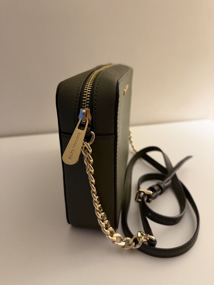 Michael Kors Green Crossbody Bag (Category: Cross-body Bags) located in Calamba. Submitted by wendyxdiane (Listing ID 1465825536, Image 2). Description: - Brand: Michael Kors - Color: Dark Olive Green - Material: Durable Saffiano leather - Hardware: Gold-tone with chain strap details - Strap: Includes adjustable leather shoulder strap - Closure: Zip top with engraved zipper pull - Condition: Clean exterior and corners, zero scratches on front met