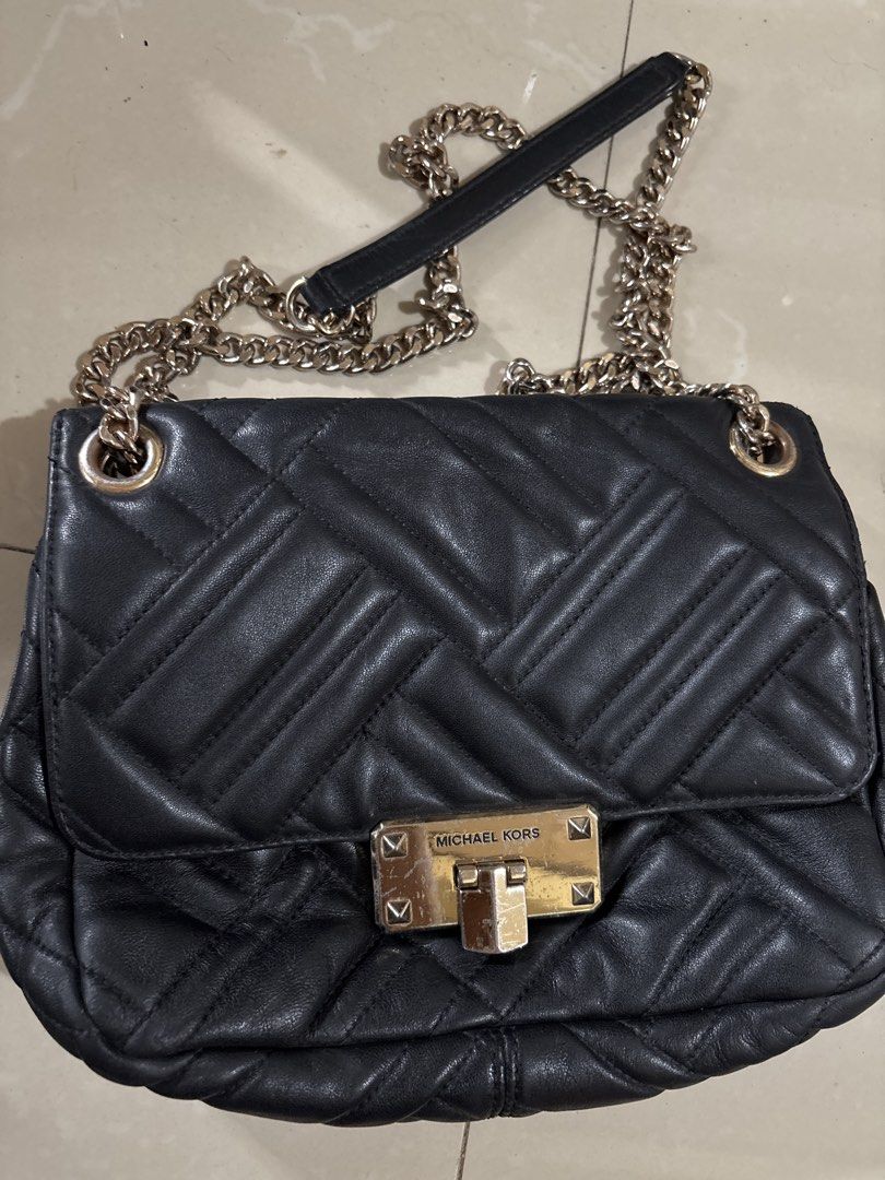 Michael Kors Quilted Black Leather Chain Shoulder Bag (Category: Luxury Bags & Wallets) located in Caloocan City. Submitted by sgnrkb (Listing ID 1465809913, Image 1). Description: - Brand: Michael Kors - Material: Soft black quilted leather - Hardware: Gold-tone metal with noticeable scratches and wear on the front clasp lock - Strap: Heavy chain strap mixed with black leather - Design: Structured shape with a front flap closure and a spacious i