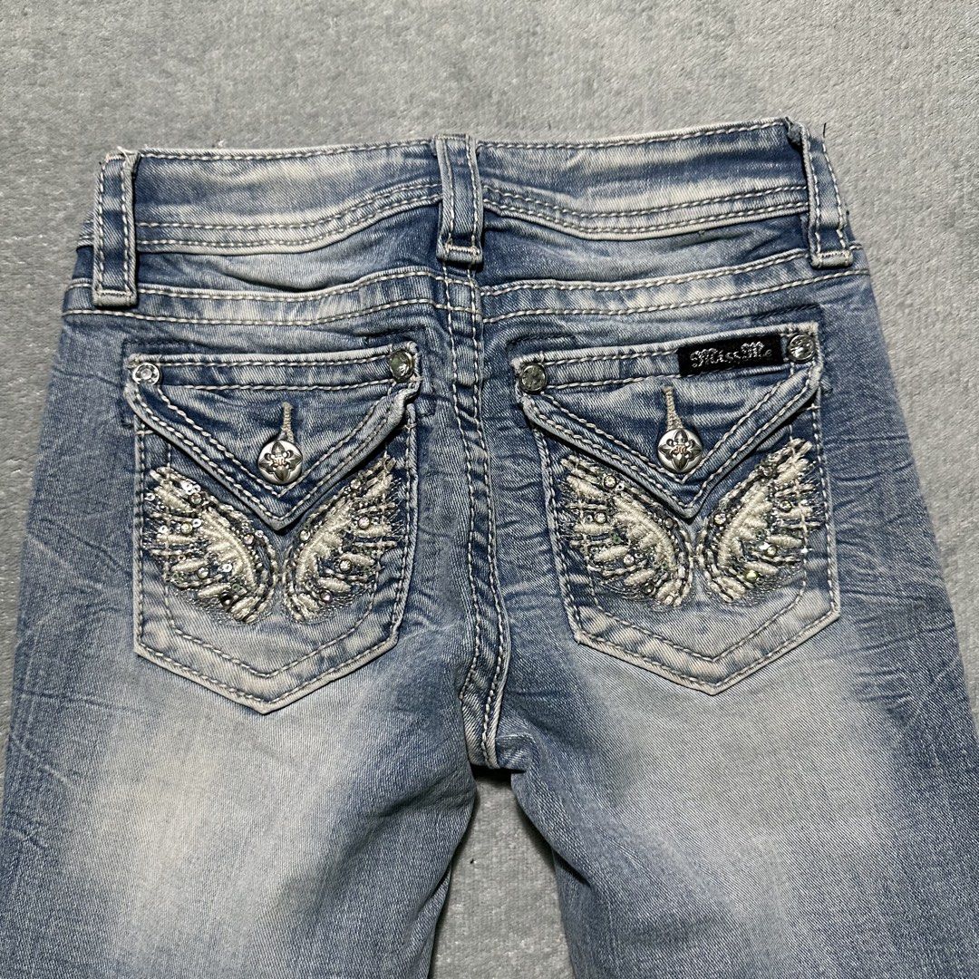 Miss Me Bootcut Jeans Size 8 (Category: Jeans) located in Villaverde. Submitted by bakatzy_secondhand_garments (Listing ID 1465886458, Image 3). Description: - Brand/Model: Miss Me Girls Bootcut Jeans (Style: K3080BG, Color: L186) - Size: 8 (Tag at waist) - Wash: Medium wash with stylish light fading on thighs and knees - Details: Eye-catching rhinestone wing embellished button-flap back pockets and contrast white stitching - Material: 92% cotton