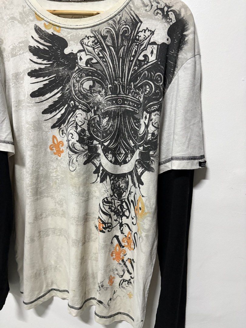 MMA Elite Long Sleeve Layered Graphic Tee (Category: Tshirts & Polo Shirts ) located in Manila. Submitted by swag_shop00 (Listing ID 1465810830, Image 2). Description: - Brand: MMA Elite - Style: Long sleeve layered t-shirt (white with contrast black sleeves) - Design: Large winged fleur-de-lis graphic print on front and back - Size: XL - Fit: Regular fit, crew neck - Material: Cotton and polyester blend.