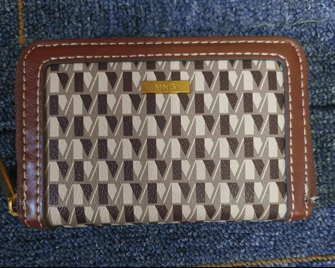 MNG patterned zip-around wallet (Category: Wallets & Card holders) located in Manila. Submitted by fiercebird_38dcf5 (Listing ID 1465882262, Image 1). Description: - Brand: MNG - Design: Brown and cream geometric pattern with gold-tone hardware and metal brand plaque - Closure: Secure zip-around closure - Interior: Multiple card slots, slip pockets, dark grey lining, and a central zippered coin compartment - Size: Compact, fits easily into most b