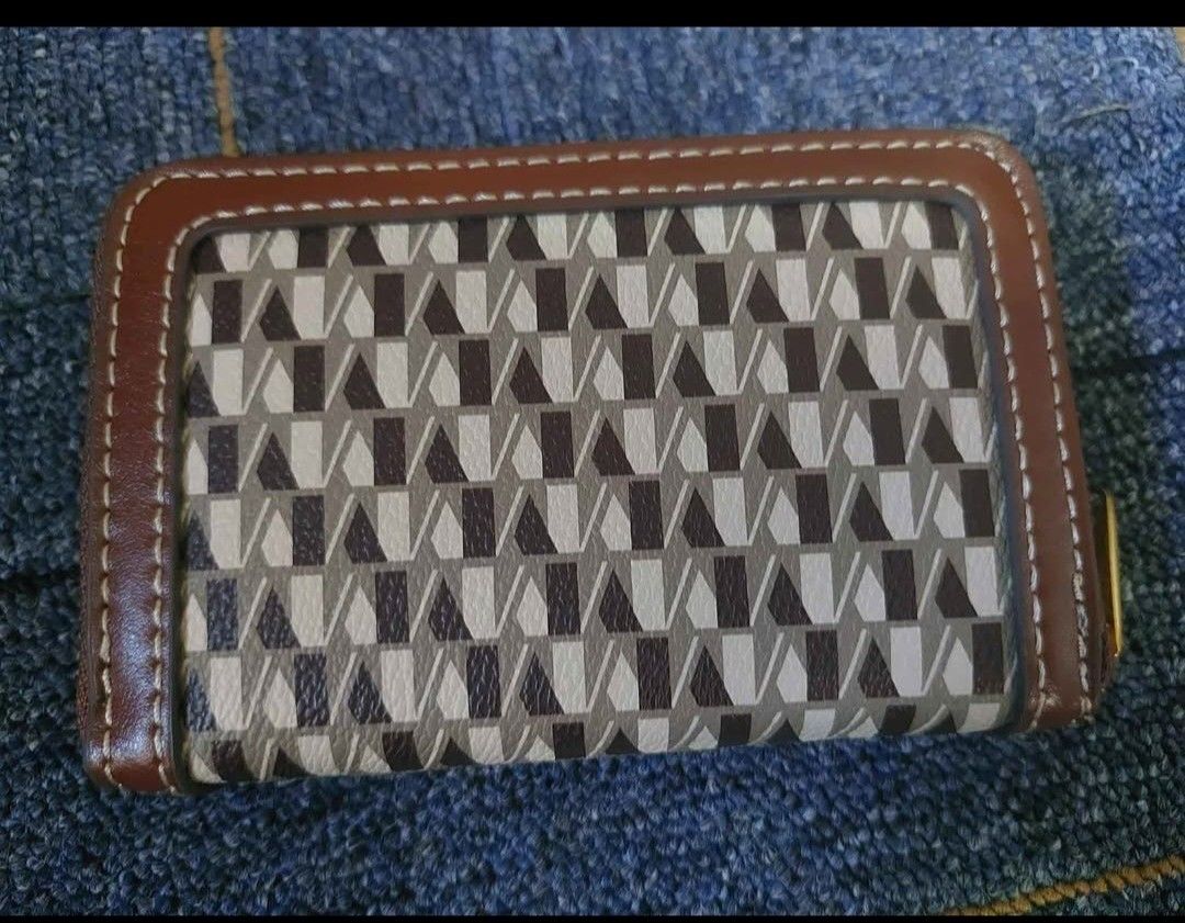 MNG patterned zip-around wallet (Category: Wallets & Card holders) located in Manila. Submitted by fiercebird_38dcf5 (Listing ID 1465882262, Image 2). Description: - Brand: MNG - Design: Brown and cream geometric pattern with gold-tone hardware and metal brand plaque - Closure: Secure zip-around closure - Interior: Multiple card slots, slip pockets, dark grey lining, and a central zippered coin compartment - Size: Compact, fits easily into most b