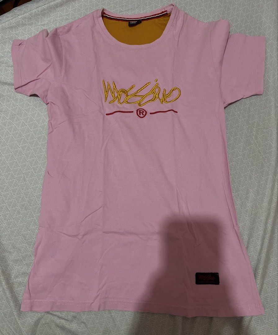Mossimo Pink T-Shirt Size M (Category: Shirts) located in Manila. Submitted by kaceylgt (Listing ID 1465924506, Image 1). Description: - Brand: Mossimo - Color: Pink with yellow and mustard yellow accents - Size: M - Design: Yellow embroidered chest branding - Details: Layered mustard yellow inner collar with striped trim, plus a small fabric patch near the bottom hem - Condition: Excellent.