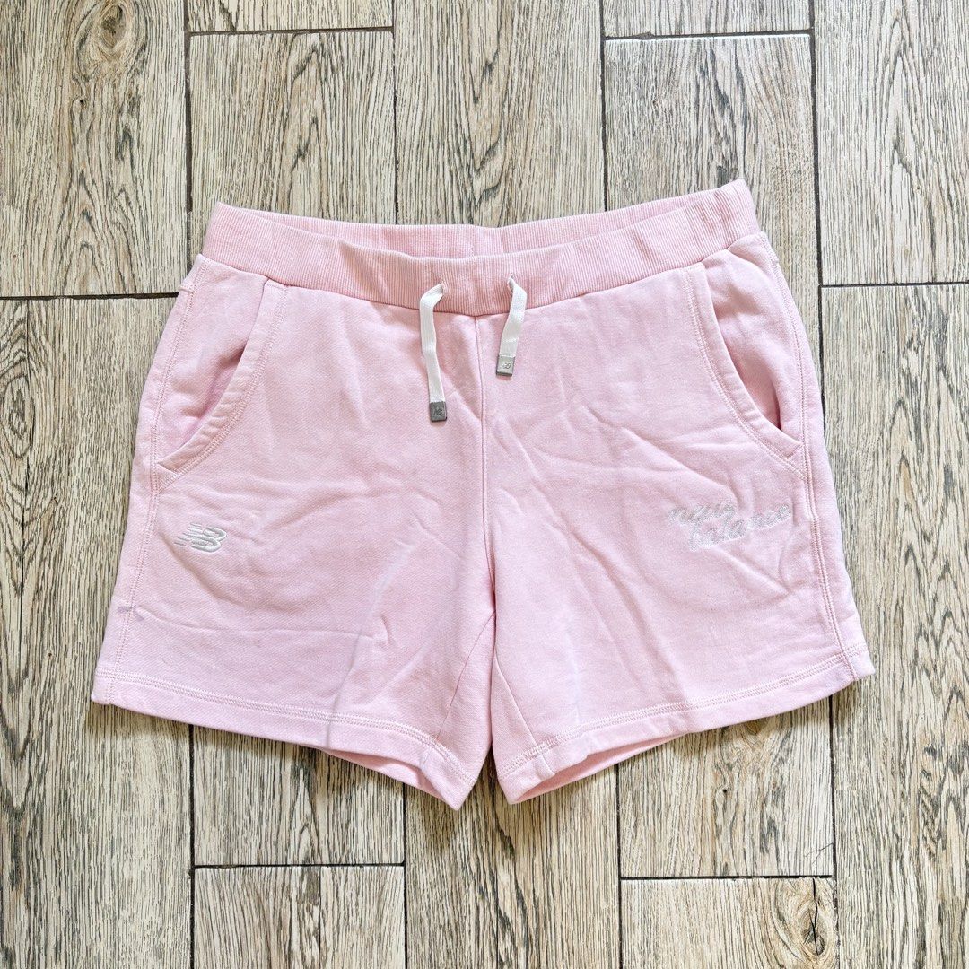 New Balance Pink Shorts (Category: Shorts) located in Imus. Submitted by reloved.nd (Listing ID 1465812111, Image 1). Description: - Brand: New Balance - Color: Soft pink - Material: Comfortable cotton - Features: Elastic waistband with white metallic-tipped drawstring, two front hand pockets - Details: Small embroidered logo on right leg and script lettering on left - Condition/Fit: Relaxed and cozy, ideal for lounging or casual wear.