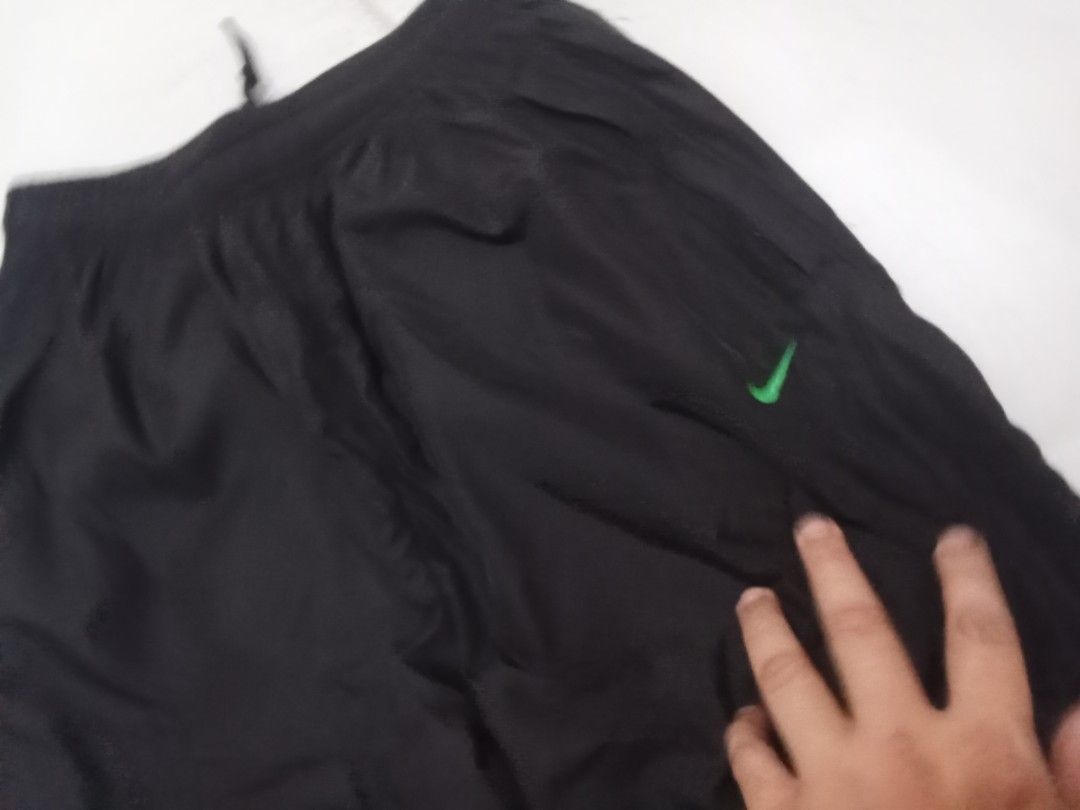 Nike Black Athletic Shorts (Category: Shorts) located in Manila. Submitted by kitkathrift (Listing ID 1465869374, Image 2). Description: - Brand: Nike - Style: Athletic shorts / knee-length capri - Color: Black with green Nike swoosh and side text graphic - Waistband: Elastic with adjustable drawstring - Material: Lightweight nylon - Condition: Good, ready to wear - Features: Size tag intact inside, ideal for workouts or casual days.