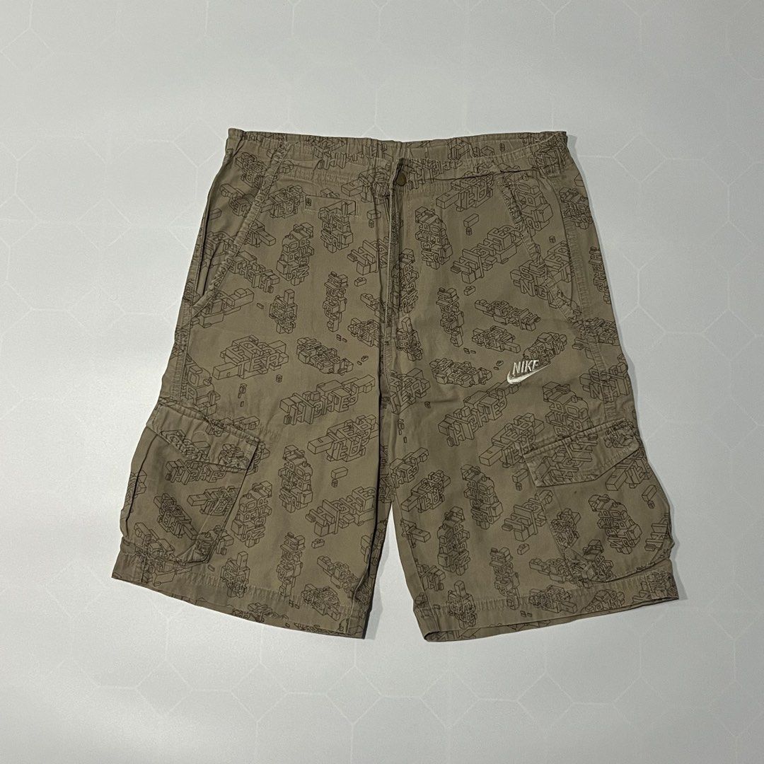 Nike Cargo Shorts Brown Geometric Print (Category: Shorts) located in Caloocan City. Submitted by lostarchive_55 (Listing ID 1465919197, Image 1). Description: Nike cargo shorts in khaki brown. All-over geometric block graphic print. Multi-pocket design with cargo pockets on the sides and back patch pockets. Elastic waistband detailing with button closure and zip fly. White Nike swoosh logo embroidered near the left pocket. Youth size L, fits age