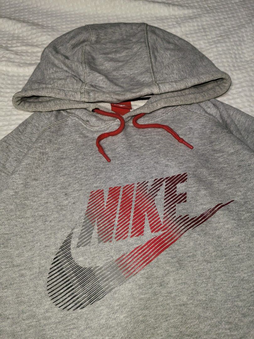 Nike Grey Gradient Swoosh Logo Pullover Hoodie Size L (Category: Hoodies) located in Mabitac. Submitted by kitothrifty (Listing ID 1465862729, Image 2). Description: - Size: Large - Color: Grey with red and black gradient logo - Material: 100% cotton body for comfort - Features: Red drawstrings with branded metal aglets, front kangaroo pocket, ribbed cuffs and hem - Origin: Made in China - Style: Classic streetwear piece.