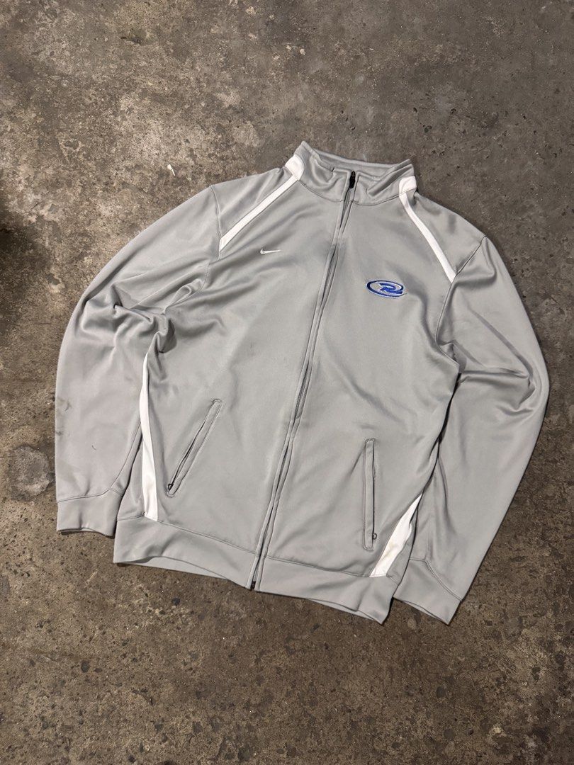 Nike Team Fit Dry Zip Jacket Grey Size M (Category: Coats, Jackets and Outerwear) located in Pasig City. Submitted by dripthrift1600 (Listing ID 1465950175, Image 1). Description: - Brand: Nike - Style: Team Fit Dry zip jacket - Color: Grey with white piping and blue logo graphic - Size: Medium - Features: High collar, full zip closure, and side pockets - Condition: Pre-loved with stains on the lower left sleeve near the cuff - Dimes: 22x26.