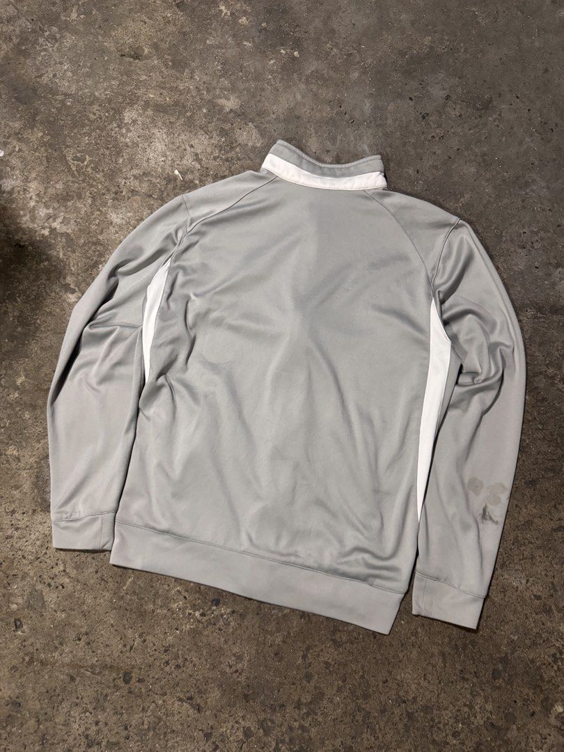 Nike Team Fit Dry Zip Jacket Grey Size M (Category: Coats, Jackets and Outerwear) located in Pasig City. Submitted by dripthrift1600 (Listing ID 1465950175, Image 2). Description: - Brand: Nike - Style: Team Fit Dry zip jacket - Color: Grey with white piping and blue logo graphic - Size: Medium - Features: High collar, full zip closure, and side pockets - Condition: Pre-loved with stains on the lower left sleeve near the cuff - Dimes: 22x26.