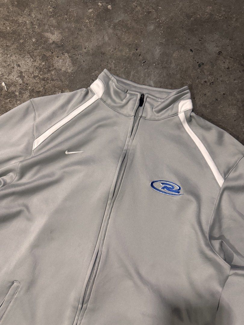 Nike Team Fit Dry Zip Jacket Grey Size M (Category: Coats, Jackets and Outerwear) located in Pasig City. Submitted by dripthrift1600 (Listing ID 1465950175, Image 3). Description: - Brand: Nike - Style: Team Fit Dry zip jacket - Color: Grey with white piping and blue logo graphic - Size: Medium - Features: High collar, full zip closure, and side pockets - Condition: Pre-loved with stains on the lower left sleeve near the cuff - Dimes: 22x26.