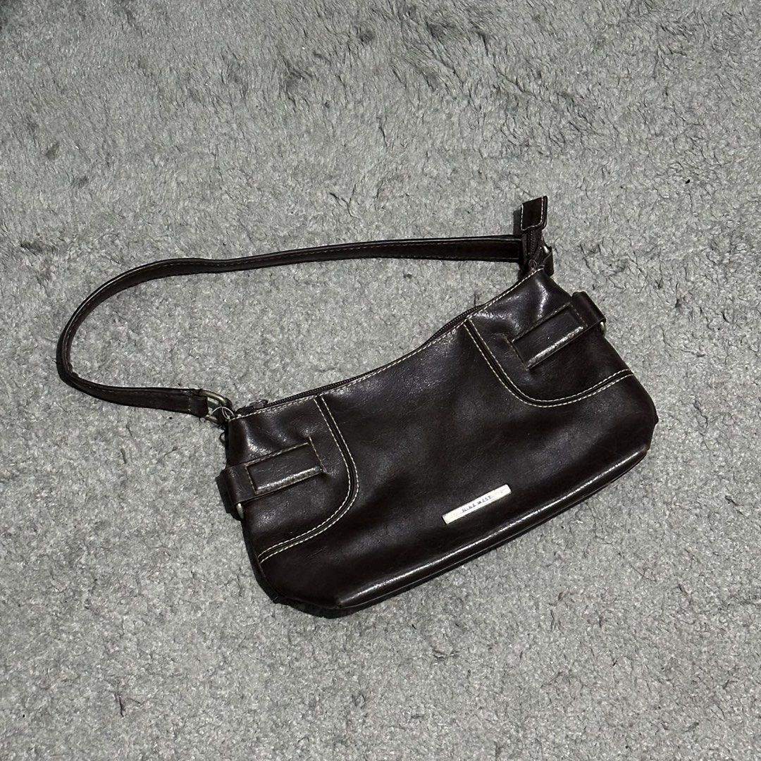 Nine West Brown Leather Shoulder Bag (Category: Shoulder Bags) located in Lipa City. Submitted by jecoparra (Listing ID 1465835790, Image 2). Description: - Brand: Nine West - Material: Dark brown faux leather with chic white contrast stitching - Hardware: Small silver-tone metal logo plate and buckle accents on sides - Straps: Comfortable double strap design - Closure: Secure top zipper closure - Interior: Clean lining, compact size ideal for da