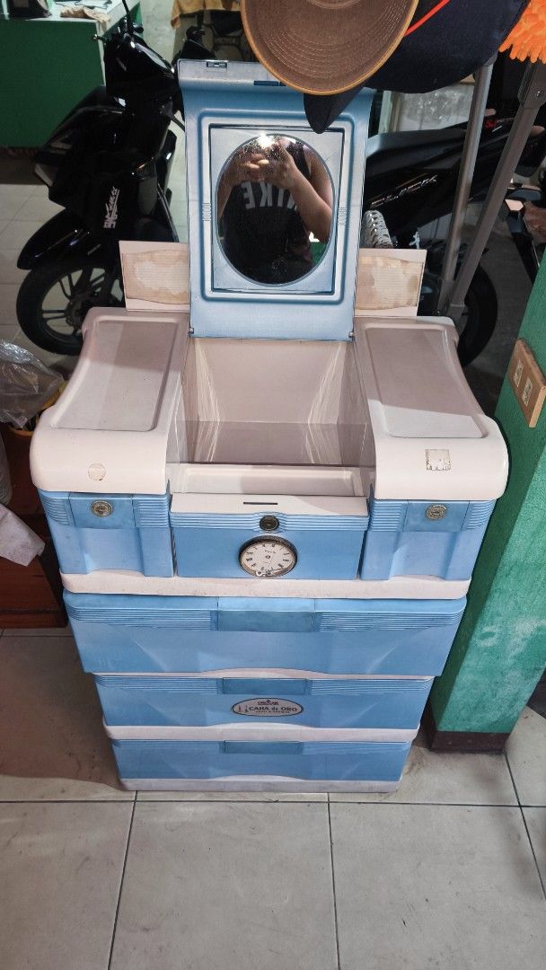 Orocan Caha de Oro Plastic Cabinet with Mirror (Category: Shelves, Cabinets & Racks) located in Bacoor. Submitted by fitatintin (Listing ID 1465935896, Image 1). Description: - Authentic Orocan Caha de Oro storage cabinet in stylish blue and white - 3 spacious bottom drawers for clothes and larger items - Convenient top compartment featuring a built-in mirror and smaller slots for makeup and accessories - Charming decorative clock design detail o