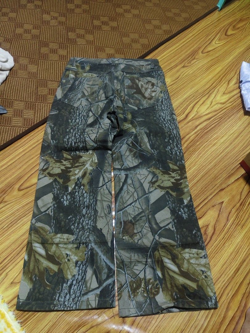 Outfitter Ridge Tree Camo Pants Size 10R (Category: Jeans) located in Santiago. Submitted by thriftnimey03 (Listing ID 1465902242, Image 2). Description: - Brand/Style: Outfitter Ridge camo pants with realistic tree bark and oak leaf pattern - Size: 10R - Material: 100% cotton for breathable comfort - Fit: Mid-rise waist with belt loops, button closure, and straight leg cut - Durability: Features reinforced knee panels - Origin: Made in China - C