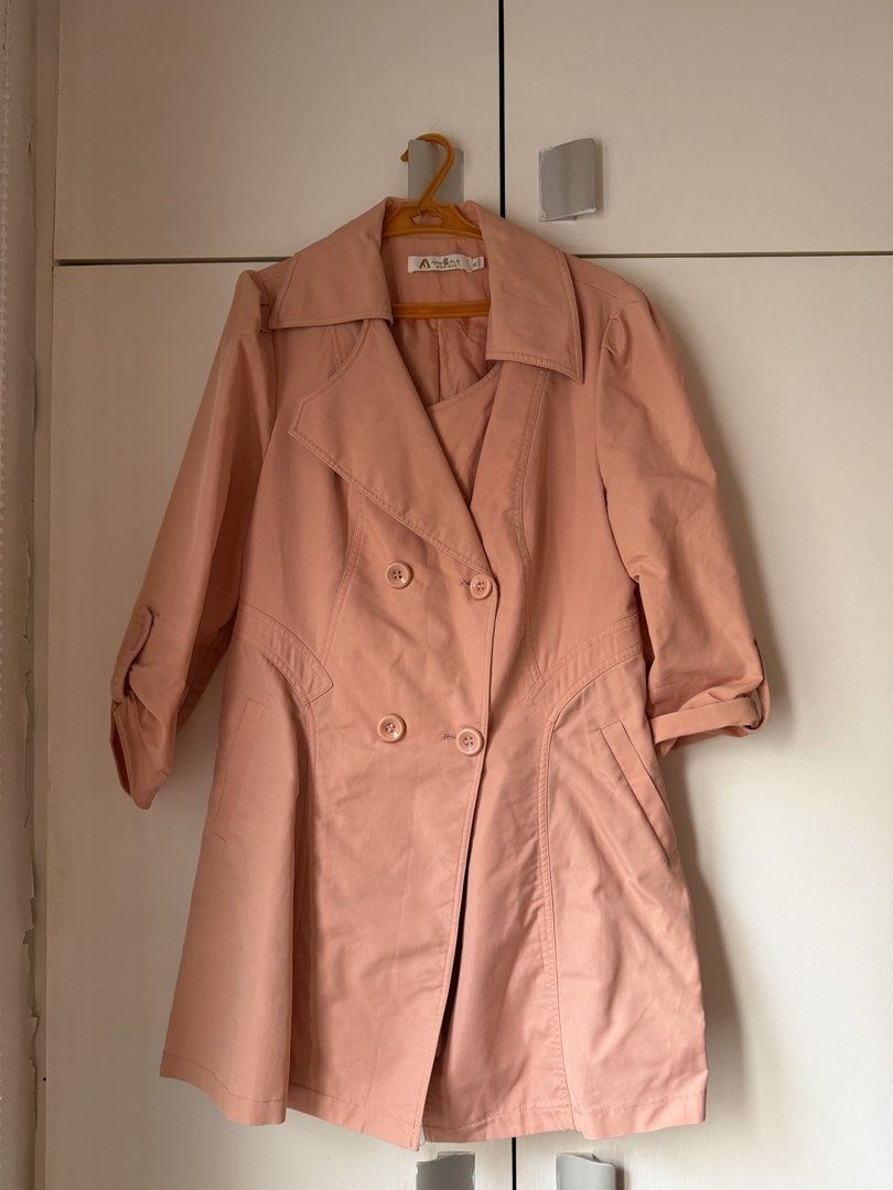 Pink double-breasted trench coat with lapel collar (Category: Coats, Jackets and Outerwear) located in Cainta. Submitted by jerichoesguerra (Listing ID 1465921086, Image 1). Description: - Color: Peach pink - Style: Double-breasted trench coat with broad lapel collar - Fit: Structured fit, lightweight material - Details: Two front pockets, button strap details on sleeves - Perfect for: Stylish layering during cooler weather.