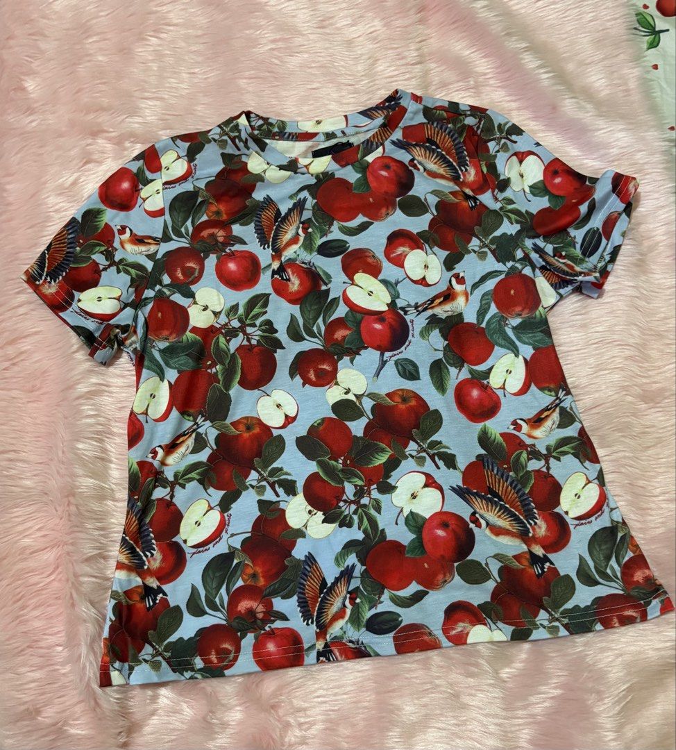 Plains & Prints Apple Print Tee (Category: Shirts) located in Tuguegarao City. Submitted by closet_jz (Listing ID 1465874726, Image 2). Description: - Brand: Plains & Prints - Size: S - Color/Design: Light blue with all-over apple and bird graphic print - Neckline: Round neckline - Material: 95% polyester, 5% cotton - Condition: Brand new with tag still attached.