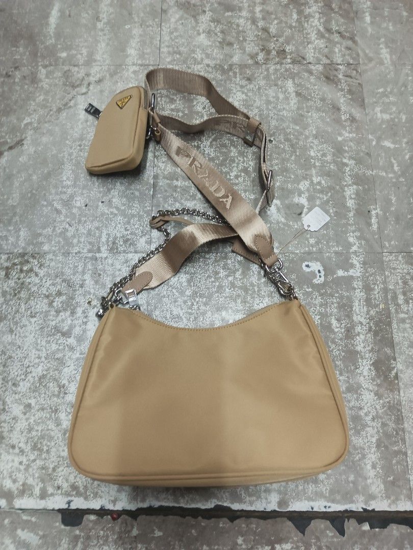 Prada Beige Nylon Re-Edition Shoulder Bag with Chain (Category: Luxury Bags & Wallets) located in Baguio. Submitted by brandeditems16 (Listing ID 1465945552, Image 2). Description: - Authentic Prada nylon shoulder bag in classic beige - Silver-tone hardware and top zip closure - Includes two interchangeable straps: thick branded strap and elegant chain strap - Comes with a small detachable pouch for extra functionality - Interior lined with signa