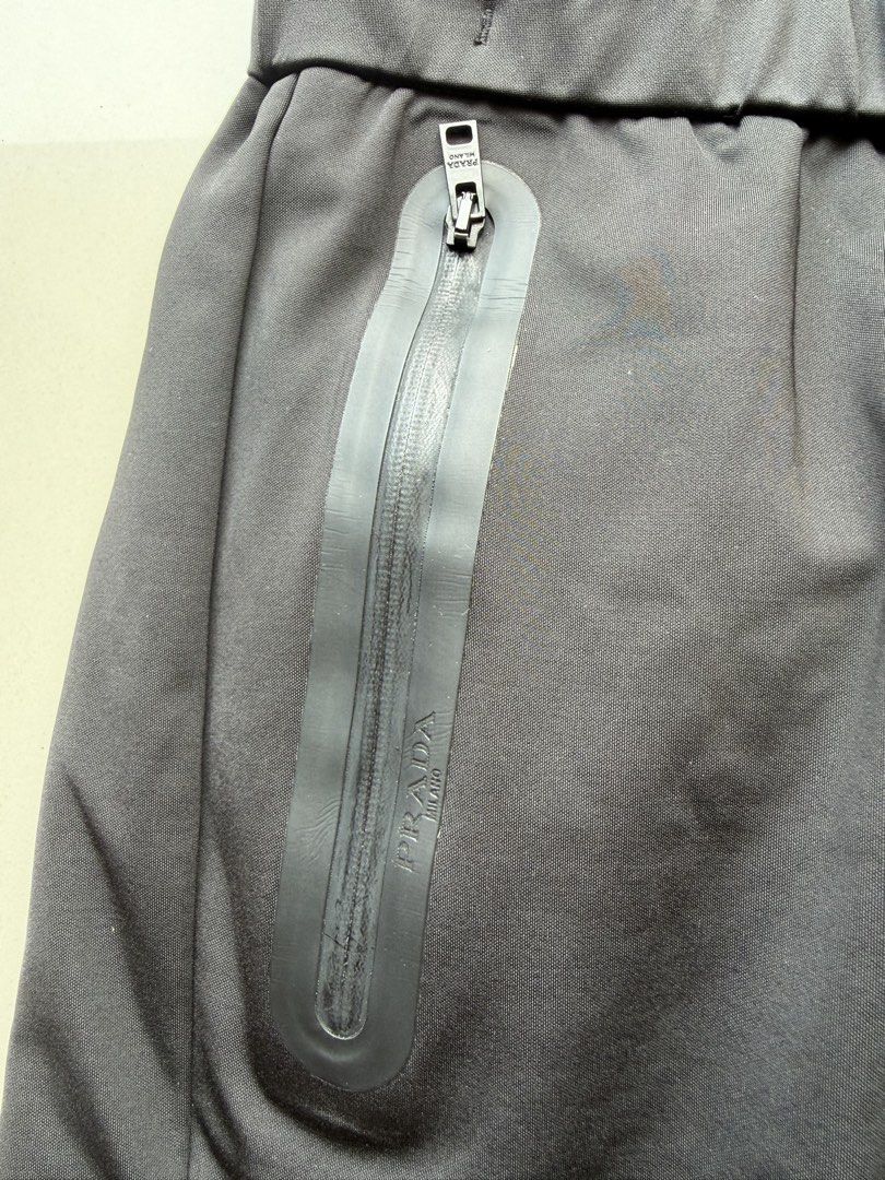 Prada Black Jogger Pants (Category: Joggers) located in Lipa City. Submitted by cokelight11 (Listing ID 1465799886, Image 3). Description: - Brand: Prada - Color: Black - Material: Premium technical fabric with comfortable stretch - Waistband: Elasticated with adjustable drawstring cords (32-36) - Pockets: Dual side pockets with waterproof zippers, Prada Milano branding, and riri hardware - Branding: Iconic red rubber Prada logo patch on the left
