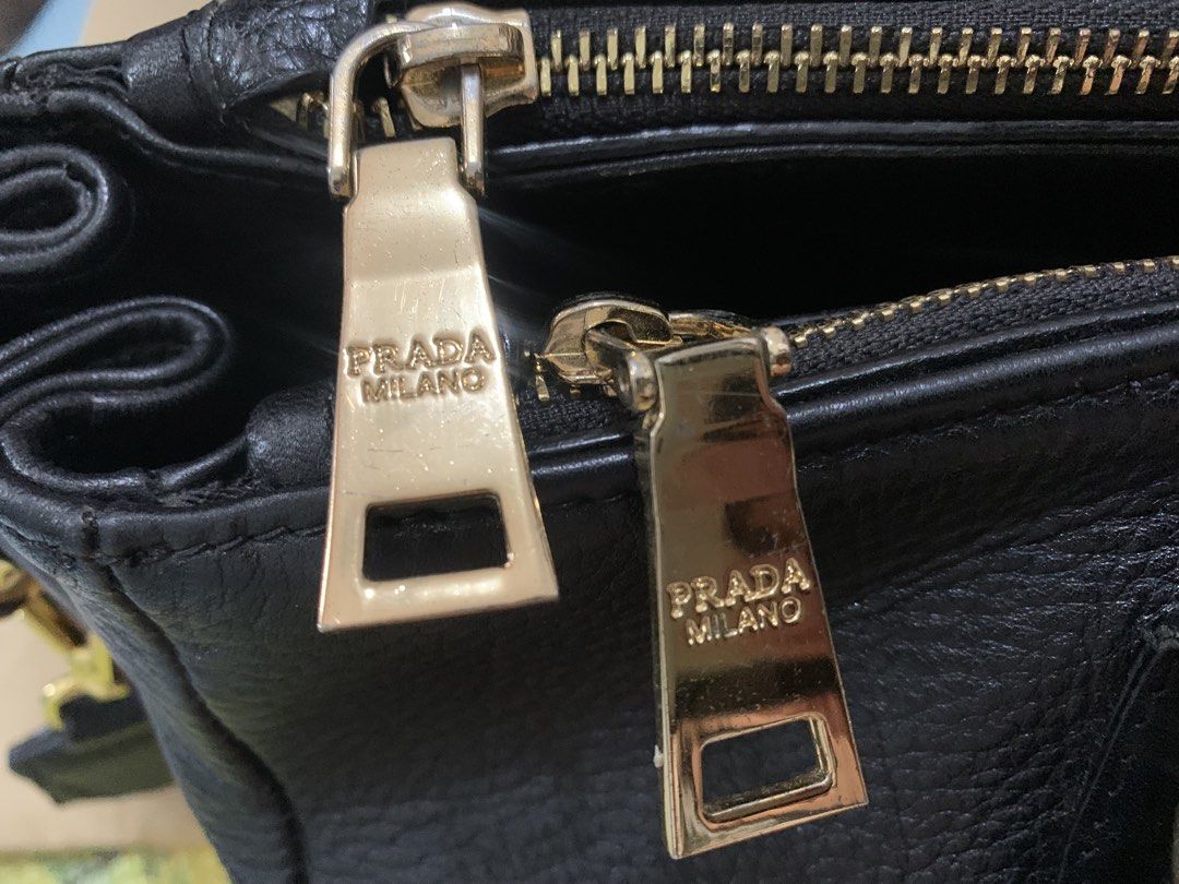 Prada Black Leather Handbag with Striped Strap (Category: Luxury Bags & Wallets) located in Marikina City. Submitted by sundaysantos (Listing ID 1465773374, Image 2). Description: - Authentic Prada handbag in black textured leather - Elegant gold hardware with Prada Milano logo and stamped zippers - Dual top handles and a stylish detachable striped shoulder strap - Interior features black logo fabric lining, multiple slip pockets, and a middle zi