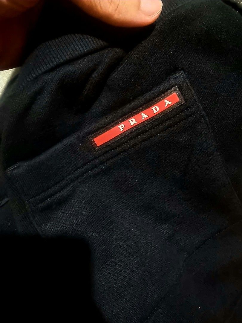 Prada Black Sweatpants with Pocket and Ankle Zips (Category: Joggers) located in Legazpi City. Submitted by rhumbalagu04057 (Listing ID 1465800423, Image 1). Description: Prada black sweatpants. Elastic waistband with drawstring. Deep side pockets plus a buttoned patch pocket on the right leg featuring the red Prada logo plaque. Zippers at the ankles with branded hardware and snap buttons. Heavyweight cotton fleece material..