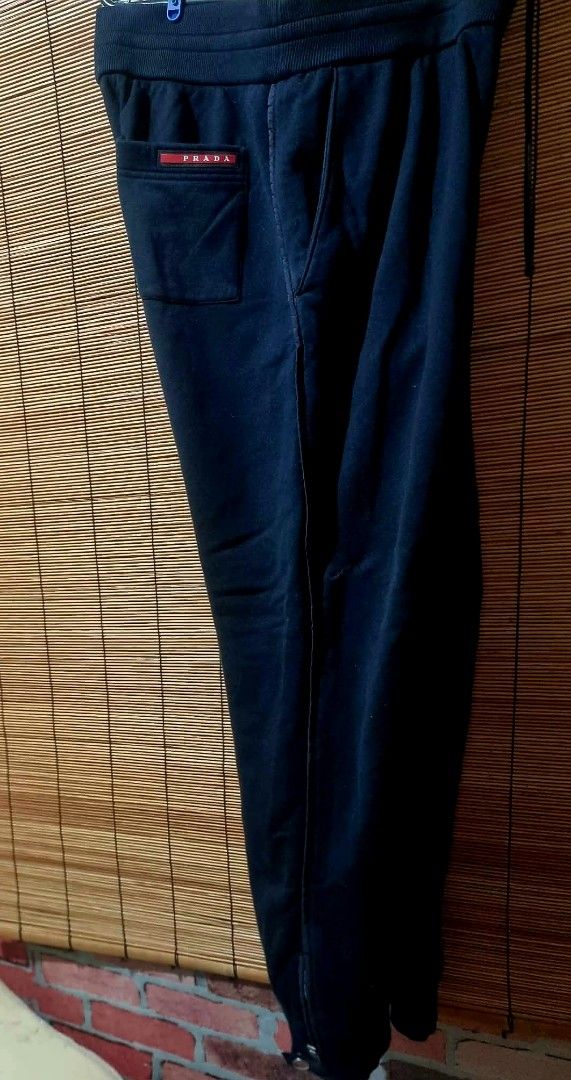 Prada Black Sweatpants with Pocket and Ankle Zips (Category: Joggers) located in Legazpi City. Submitted by rhumbalagu04057 (Listing ID 1465800423, Image 2). Description: Prada black sweatpants. Elastic waistband with drawstring. Deep side pockets plus a buttoned patch pocket on the right leg featuring the red Prada logo plaque. Zippers at the ankles with branded hardware and snap buttons. Heavyweight cotton fleece material..