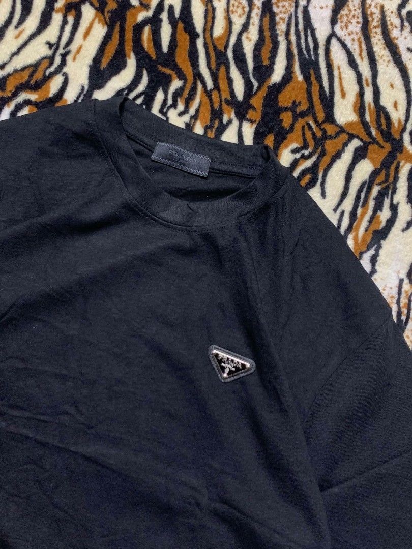 Prada Black T-Shirt with Triangle Logo (Category: Shirts) located in San Juan City. Submitted by findmorelux (Listing ID 1465858937, Image 3). Description: - Brand: Prada - Color: Classic Black - Fit: Relaxed fit with short sleeves - Material: Clean cotton jersey knit - Detail: Iconic enamel triangle logo badge on left chest - Condition: Great casual basic piece for everyday wear.