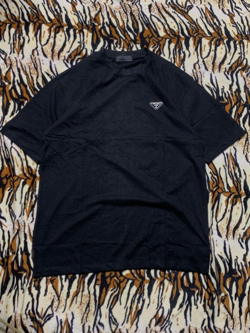 Prada Black T-Shirt with Triangle Logo (Category: Shirts) located in San Juan City. Submitted by findmorelux (Listing ID 1465858937, Image 1). Description: - Brand: Prada - Color: Classic Black - Fit: Relaxed fit with short sleeves - Material: Clean cotton jersey knit - Detail: Iconic enamel triangle logo badge on left chest - Condition: Great casual basic piece for everyday wear.