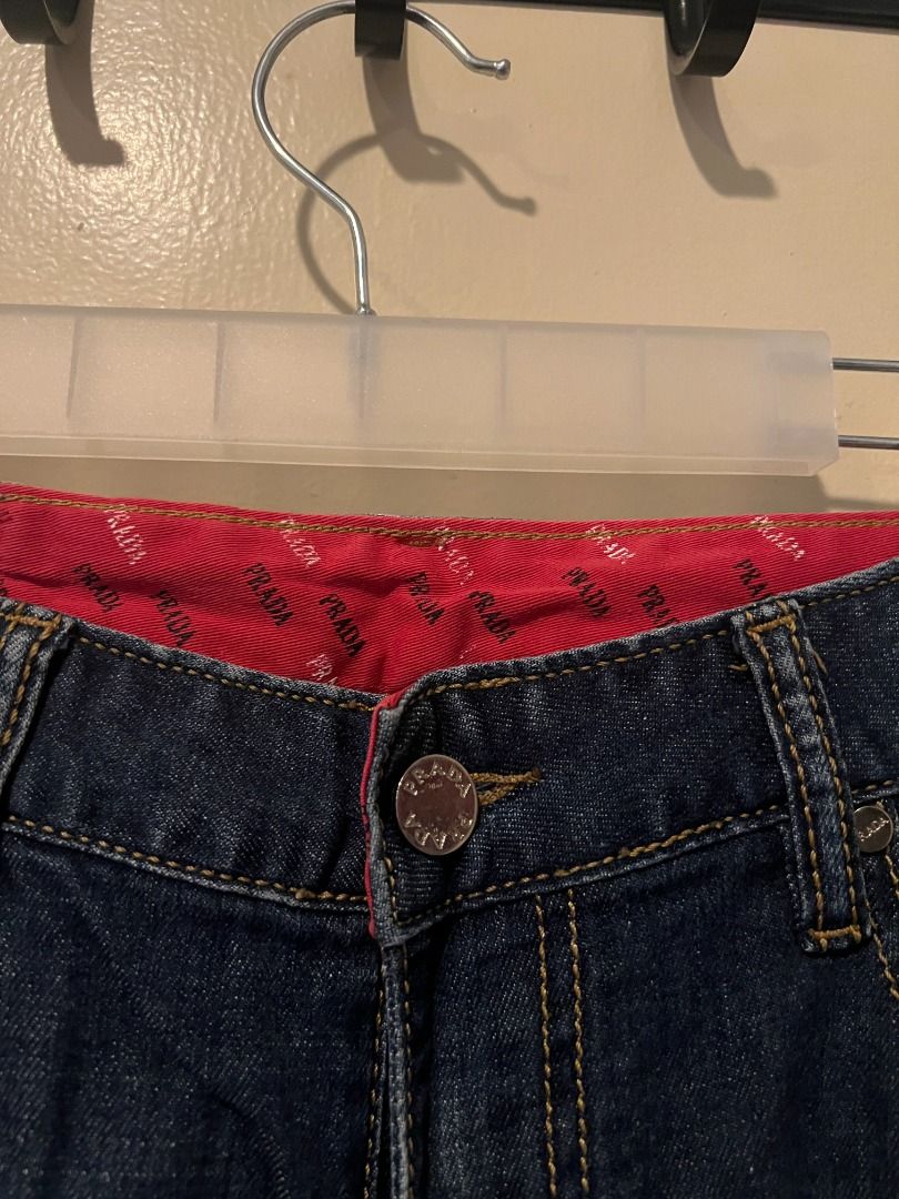 Prada Classic Fit Denim Jeans [p11] (Category: Jeans) located in Pasig City. Submitted by awesamfinds (Listing ID 1465836227, Image 2). Description: - Classic straight leg fit with timeless styling - Premium branded metal button closure and rivets - Distinctive red fabric lining inside the waistband - Back pockets feature stylish stitch details and iconic red Prada text embroidery - White brand label sewn above the back pocket area W: 40 cm flat;