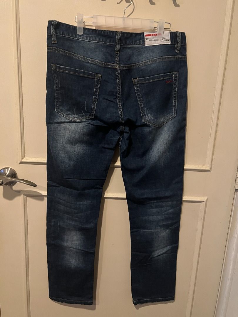 Prada Classic Fit Denim Jeans [p11] (Category: Jeans) located in Pasig City. Submitted by awesamfinds (Listing ID 1465836227, Image 3). Description: - Classic straight leg fit with timeless styling - Premium branded metal button closure and rivets - Distinctive red fabric lining inside the waistband - Back pockets feature stylish stitch details and iconic red Prada text embroidery - White brand label sewn above the back pocket area W: 40 cm flat;