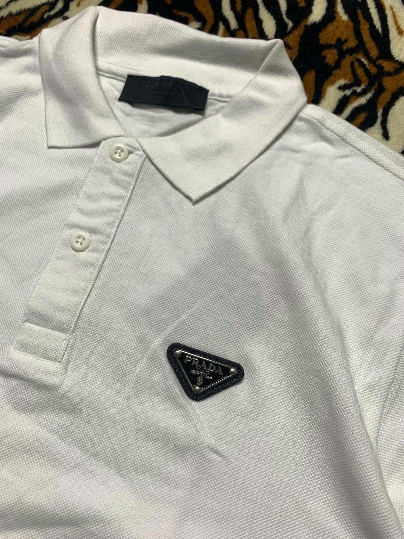 Prada White Polo Shirt with Triangle Logo (Category: Tshirts & Polo Shirts ) located in San Juan City. Submitted by findmorelux (Listing ID 1465858763, Image 3). Description: - Brand: Prada - Color: Clean White - Material: Premium cotton piqué - Design: Classic collar with 3-button placket and short sleeves - Branding: Iconic metal triangle logo plaque on the left chest - Details: Authentic black Prada Milano neck label - Condition: Pristine, wel