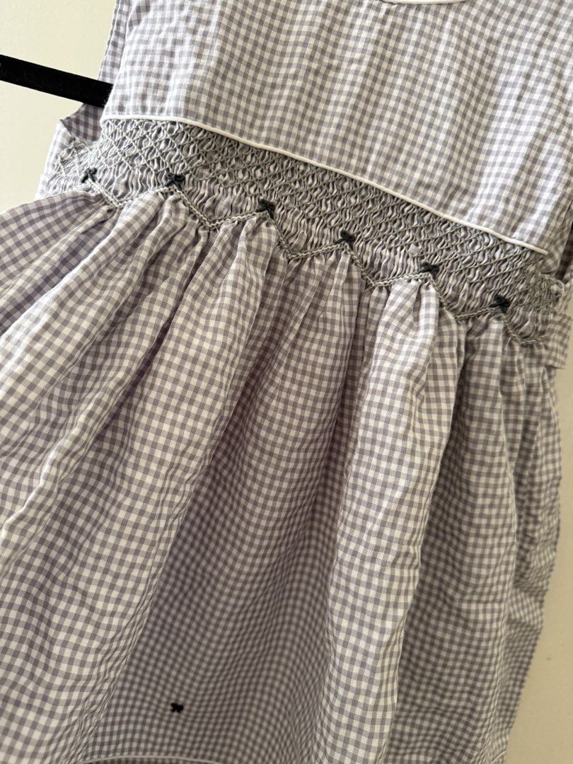 Puffy Threads PH Grey Gingham Smocked Dress Size 2 (Category: Dresses) located in Taguig. Submitted by muntingkahon (Listing ID 1465764186, Image 2). Description: - Brand: Puffy Threads PH - Size: 2 - Color/Pattern: Grey and white gingham - Details: Smocked bodice with intricate grey embroidery, white piping along neckline and hem - Cut: Sleeveless with a flared skirt - Condition: Great for casual days or special occasions.