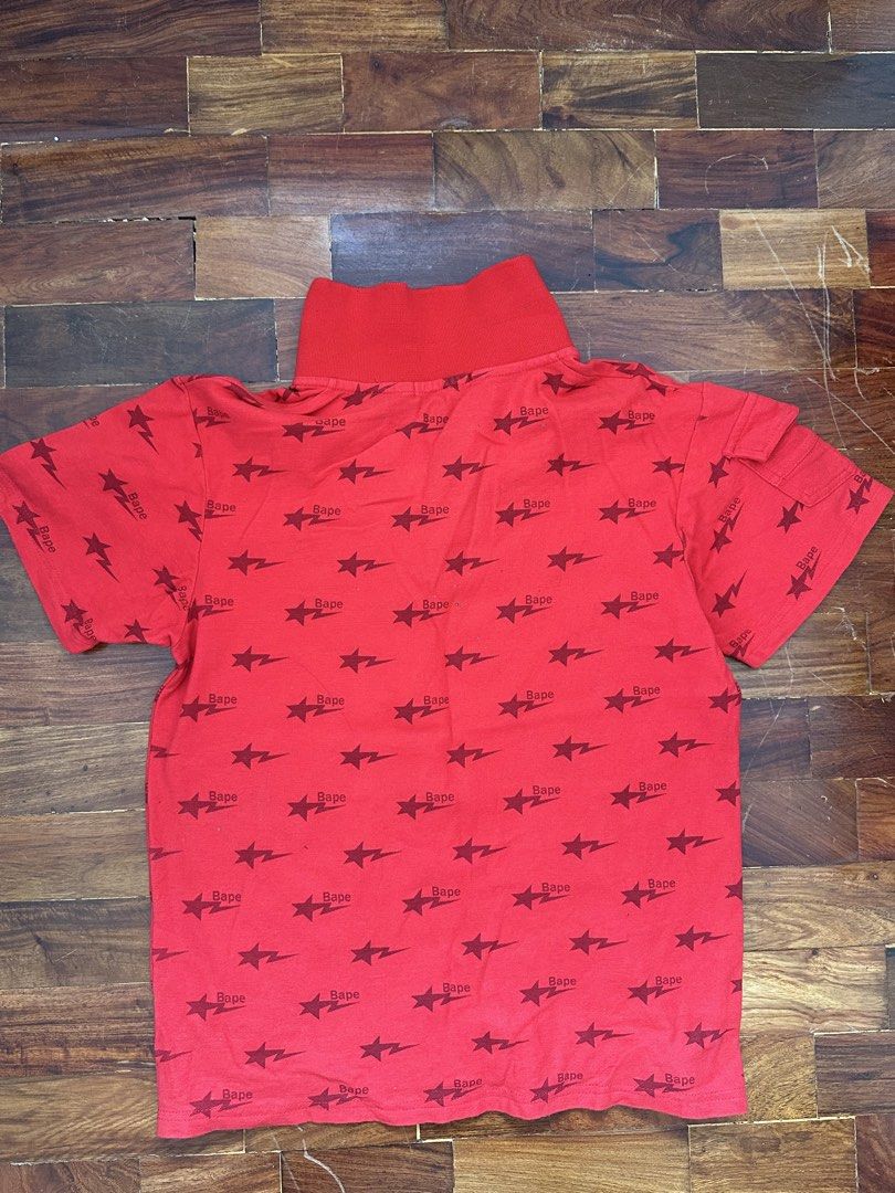 Red Bape Star Print Polo Shirt (Category: Tshirts & Polo Shirts ) located in Cainta. Submitted by buy.preloved (Listing ID 1465768477, Image 3). Description: - Color: Bright red with dark red star and Bape text all-over pattern - Details: Small embroidered ape head patch on the chest - Features: Short sleeves with a small flap pocket on one arm, red buttoned collar - Brand/Tag: Rend-Top collar tag - Condition: Pre-loved, great statement piece.