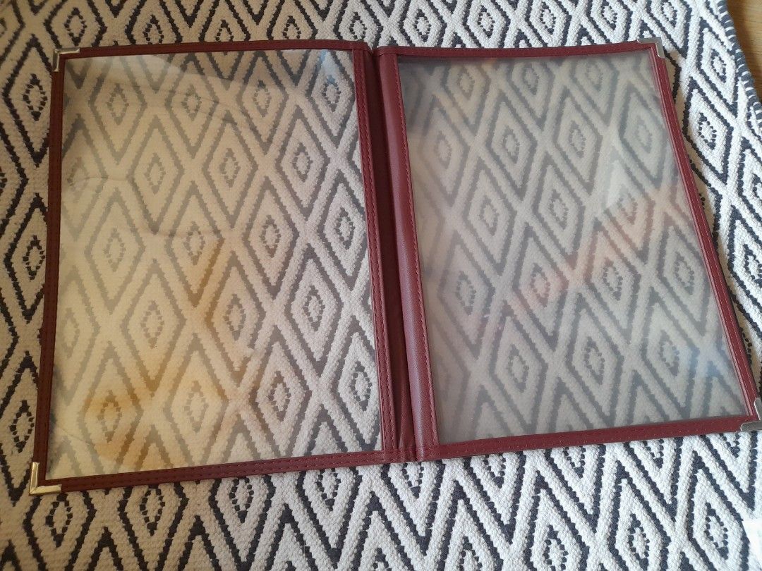 Red Leatherette Menu Cover with Clear Plastic Sleeves (Category: Stationery & School Supplies) located in Bocaue. Submitted by marajapansurplus (Listing ID 1465800248, Image 2). Description: - Color & Material: Elegant burgundy faux leather - Durability: Silver metal corner protectors on front and back - Display: Multiple clear plastic view panels for menus or price lists - Ideal For: Restaurants, cafes, and bars - Condition: Cleaned, practical, 