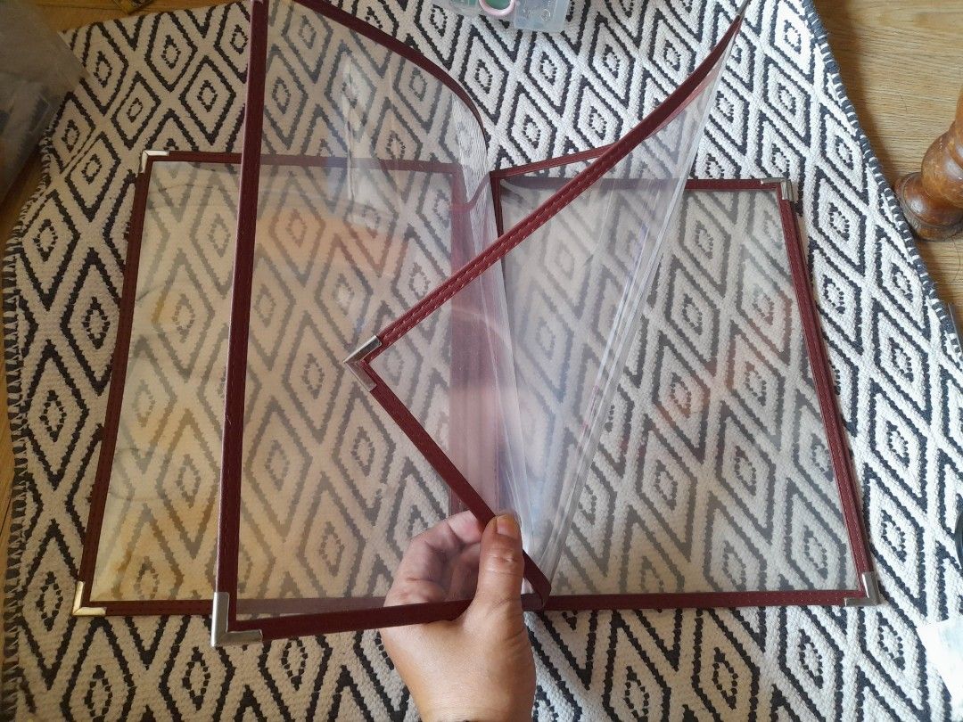 Red Leatherette Menu Cover with Clear Plastic Sleeves (Category: Stationery & School Supplies) located in Bocaue. Submitted by marajapansurplus (Listing ID 1465800248, Image 3). Description: - Color & Material: Elegant burgundy faux leather - Durability: Silver metal corner protectors on front and back - Display: Multiple clear plastic view panels for menus or price lists - Ideal For: Restaurants, cafes, and bars - Condition: Cleaned, practical, 