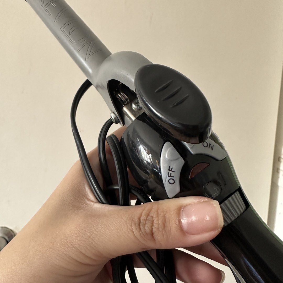 Revlon Hair Curling Iron (Category: Hair) located in Kawit. Submitted by wevibevintage (Listing ID 1465791215, Image 3). Description: Revlon curling iron with black and grey finish. Includes clamp design, easy-to-use dial temperature control, and physical on and off switches on the handle. Standard electrical plug attached. Works great for styling hair at home..