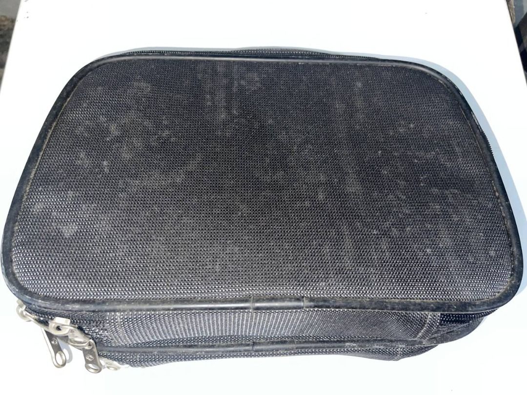 Samsonite Black Travel Pouch (Category: Belt bags, Clutches and Pouches) located in Quezon City. Submitted by randomseller09 (Listing ID 1465891213, Image 2). Description: - Samsonite travel pouch in solid black - Structured rectangular shape with secure zip-around closure and metal zipper pulls - Features a sleek metallic brand logo badge on the front - Textured fabric exterior (please note: shows minor dusty residue and light wear marks) - Stur