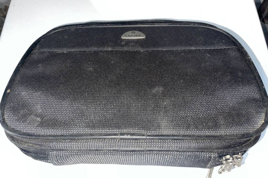 Samsonite Black Travel Pouch (Category: Belt bags, Clutches and Pouches) located in Quezon City. Submitted by randomseller09 (Listing ID 1465891213, Image 1). Description: - Samsonite travel pouch in solid black - Structured rectangular shape with secure zip-around closure and metal zipper pulls - Features a sleek metallic brand logo badge on the front - Textured fabric exterior (please note: shows minor dusty residue and light wear marks) - Stur