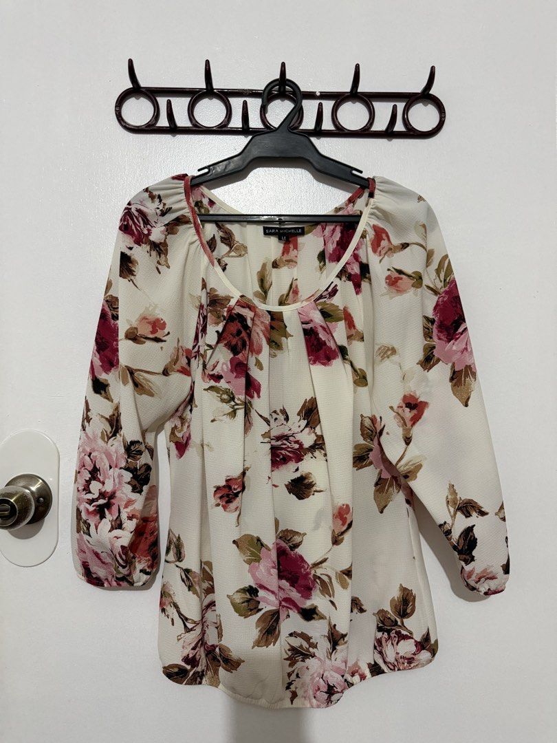 Sara Michelle Floral Print Blouse Medium (Category: Blouses) located in Las Pinas. Submitted by milkydeclutter (Listing ID 1465939718, Image 1). Description: - Brand: Sara Michelle - Size: Medium (tag attached) - Color/Pattern: Cream base with pink and red floral print - Features: Long sleeves with gathered cuffs, subtle neckline pleating - Material: Lightweight fabric, ideal for layering or solo wear - Condition: Excellent.