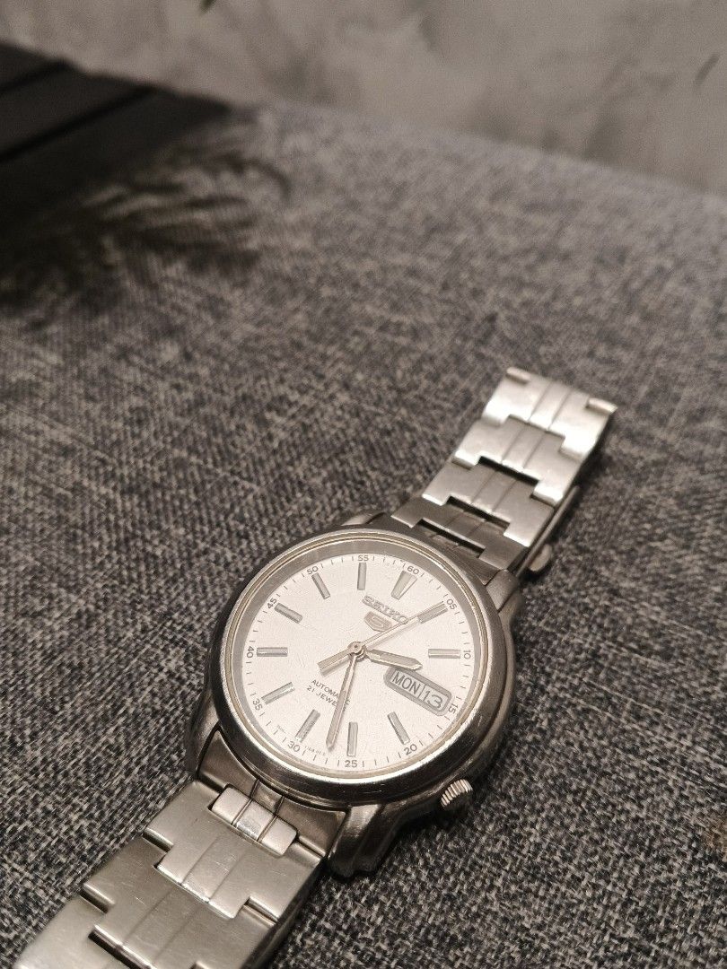 Seiko 5 Automatic 21 Jewels (Category: Men's Watches) located in Andop. Submitted by finderskeepersxzz (Listing ID 1465819744, Image 2). Description: - Brand/Model: Seiko 5 Automatic Watch - Dial: Textured white with silver-tone hands and markers - Features: Day and date display at 3 o'clock - Movement: 21-jewel automatic movement visible through exhibition case back - Material: Stainless steel case and matching bracelet strap - Closure: Standard