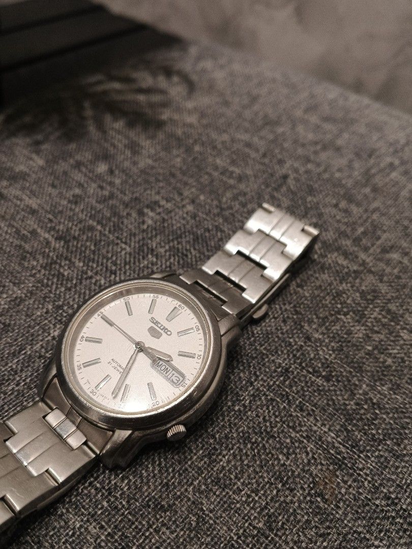 Seiko 5 Automatic 21 Jewels (Category: Men's Watches) located in Andop. Submitted by finderskeepersxzz (Listing ID 1465819744, Image 3). Description: - Brand/Model: Seiko 5 Automatic Watch - Dial: Textured white with silver-tone hands and markers - Features: Day and date display at 3 o'clock - Movement: 21-jewel automatic movement visible through exhibition case back - Material: Stainless steel case and matching bracelet strap - Closure: Standard