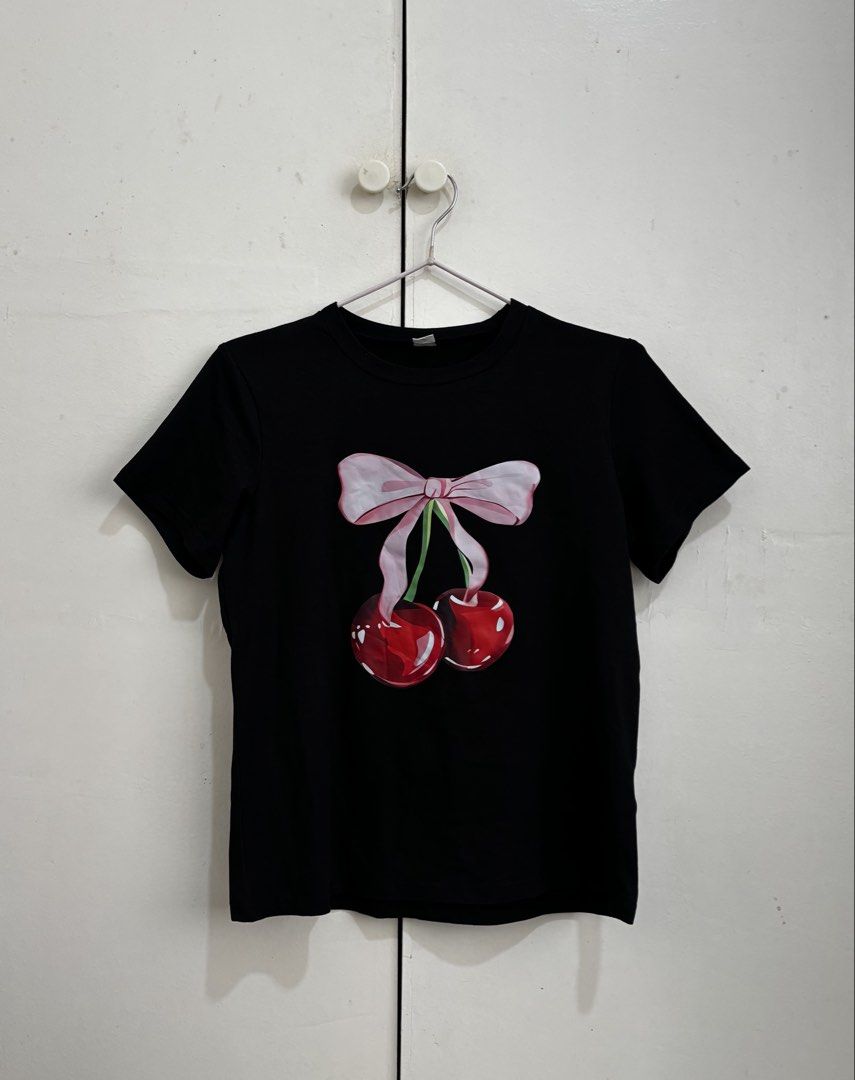 SHEIN Black Cherry Bow Graphic T-Shirt (Category: Shirts) located in Manila. Submitted by dianafayesimbre (Listing ID 1465831415, Image 3). Description: - Brand/Source: SHEIN - Size: Kids 12Y on tag but can fit small to semi large womens - Design: Pink bow and cherry graphic on front, solid black back - Cut: Short sleeves, round neckline - Condition: Brand new.