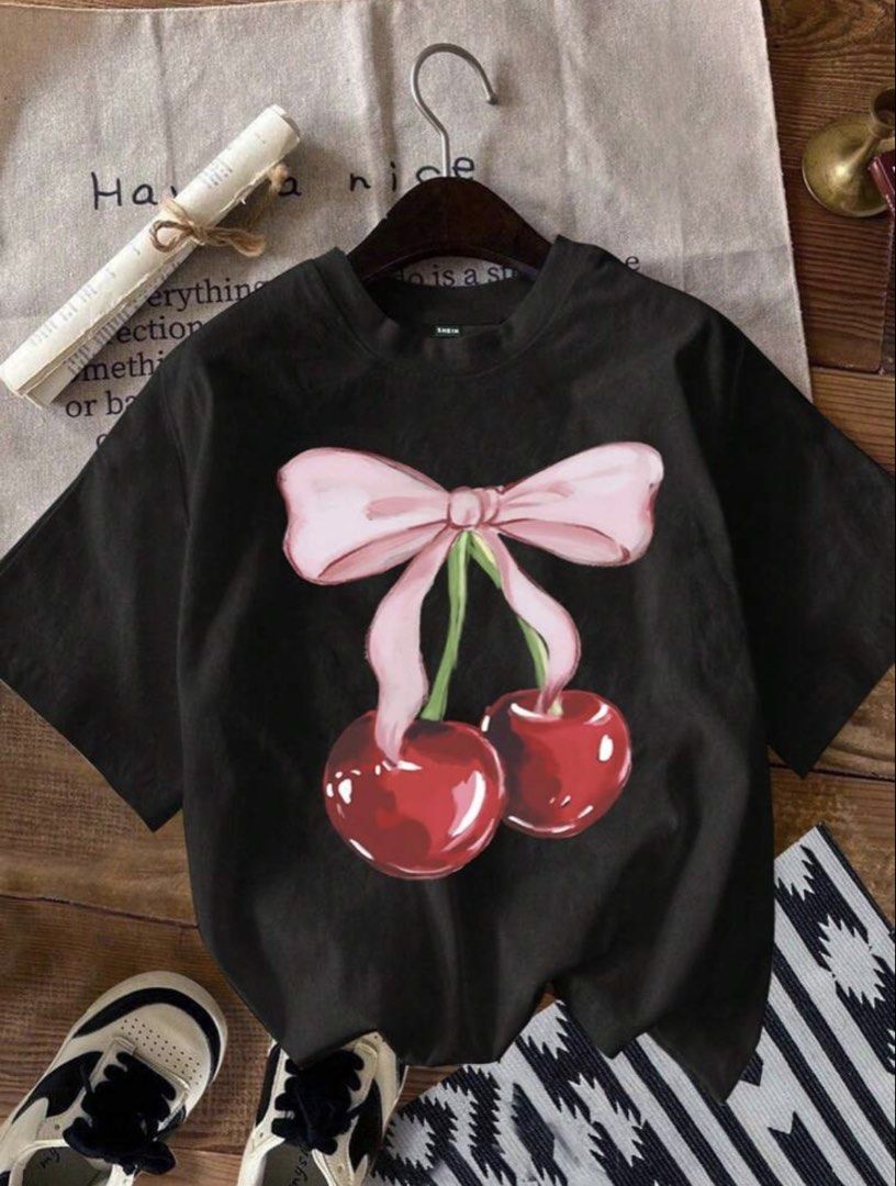 SHEIN Black Cherry Bow Graphic T-Shirt (Category: Shirts) located in Manila. Submitted by dianafayesimbre (Listing ID 1465831415, Image 2). Description: - Brand/Source: SHEIN - Size: Kids 12Y on tag but can fit small to semi large womens - Design: Pink bow and cherry graphic on front, solid black back - Cut: Short sleeves, round neckline - Condition: Brand new.