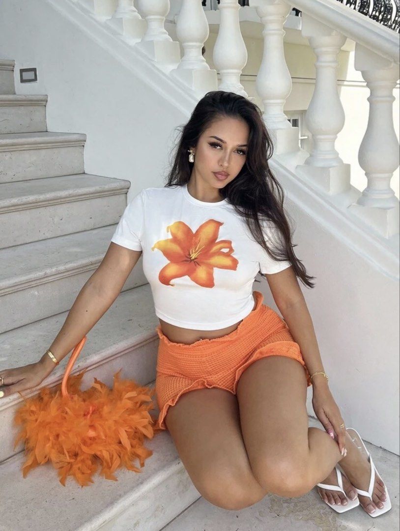 SHEIN White Crop Top Orange Flower (Category: Shirts) located in Manila. Submitted by dianafayesimbre (Listing ID 1465841556, Image 2). Description: - Brand: SHEIN - Size: Teen 15Y on tag but can fit xxs to semi medium frame womens - Design: Bold orange tiger lily graphic print - Details: Short sleeves, classic crew neck, stretchy fabric - Condition:Brand new - Styling: Perfect to pair with high-waisted shorts or jeans.