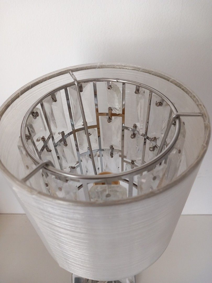 Silver Crystal Shade Table Lamp with Plug （分類：燈飾）位於 Hong Kong。 由 smartwear2ndhand 提交（商品編號 1465904674，圖片 2）。簡介： Bedside table lamp with chrome-finished metal base and stand. Cylindrical fabric shade houses reflective crystal elements inside. Clear power cord attached with standard 3-pin plug. Works great on nightstands, desks, or living room side tables. Clean look, neutral colors match most room decors. Standard bulb socket inside.。