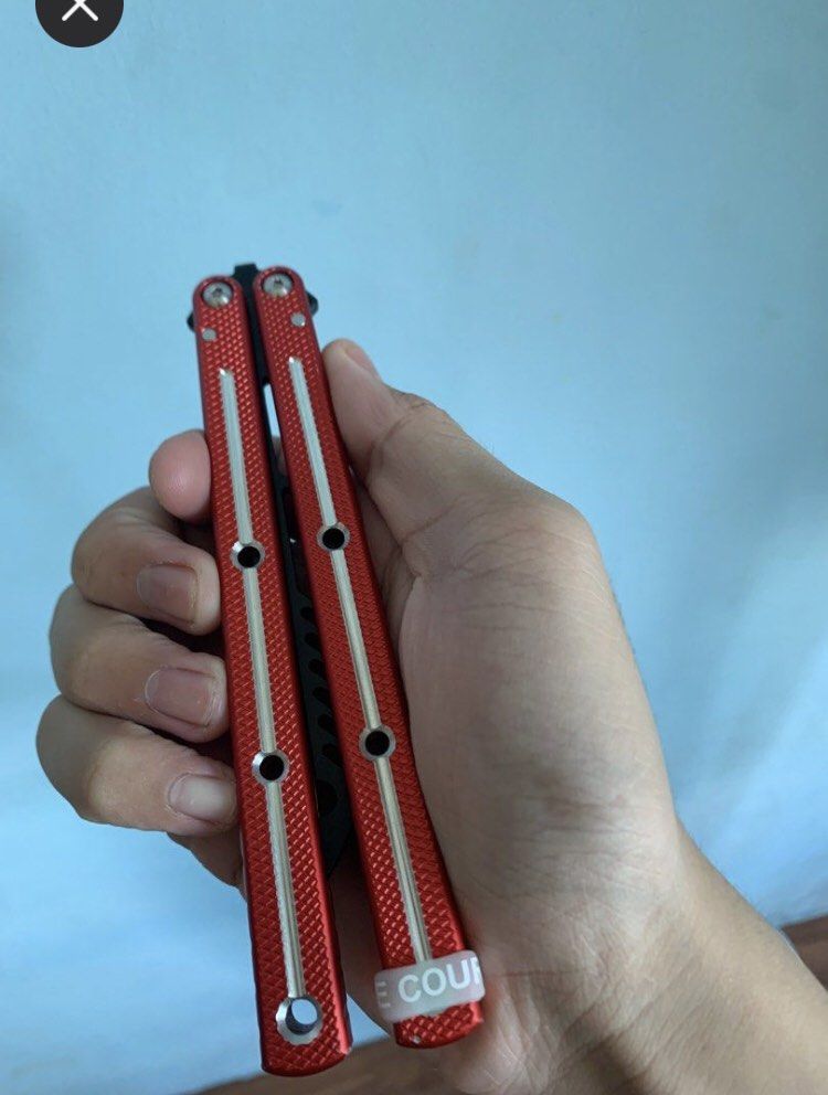 Squid Industries Krake Raken V2 Balisong Trainer Red (Category: Action & Battle Toys) located in Manila. Submitted by papelfly (Listing ID 1465915864, Image 2). Description: - Model: Squid Industries Krake Raken V2 Balisong Trainer - Colorway: Red handles with silver accents and black cutout training blade - Handle Design: Aluminum channel handles with enhanced texturing - Condition: Barely touched, flips super smoothly - Inclusions: Original box