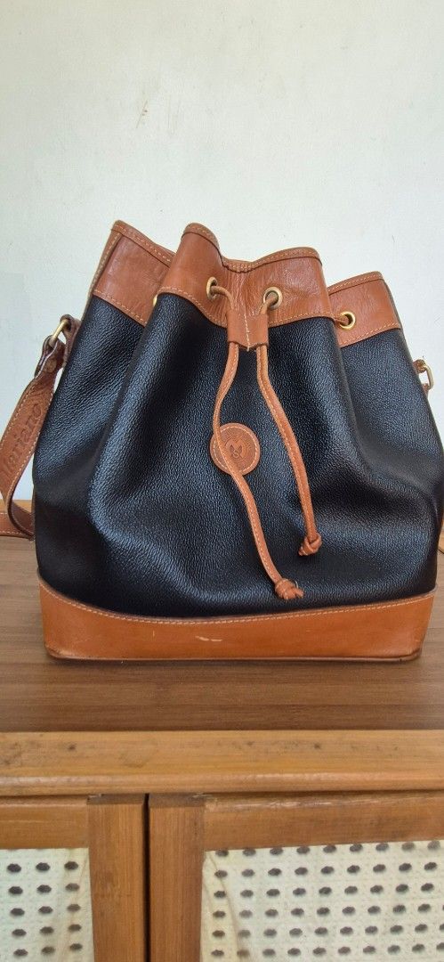 St. Marino Two-Tone Bucket Bag (Category: Shoulder Bags) located in Manila. Submitted by shandarfa49055 (Listing ID 1465839446, Image 1). Description: - Brand: St. Marino - Style: Bucket bag in black textured leather - Details: Brown leather trim and base, gold-tone eyelets, drawstring closure - Interior: Fabric lining with a zippered pocket and brand patch - Condition: Good, with some surface scuffs and scratches on the bottom brown leather port
