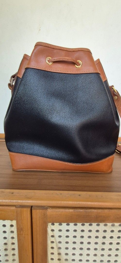 St. Marino Two-Tone Bucket Bag (Category: Shoulder Bags) located in Manila. Submitted by shandarfa49055 (Listing ID 1465839446, Image 2). Description: - Brand: St. Marino - Style: Bucket bag in black textured leather - Details: Brown leather trim and base, gold-tone eyelets, drawstring closure - Interior: Fabric lining with a zippered pocket and brand patch - Condition: Good, with some surface scuffs and scratches on the bottom brown leather port